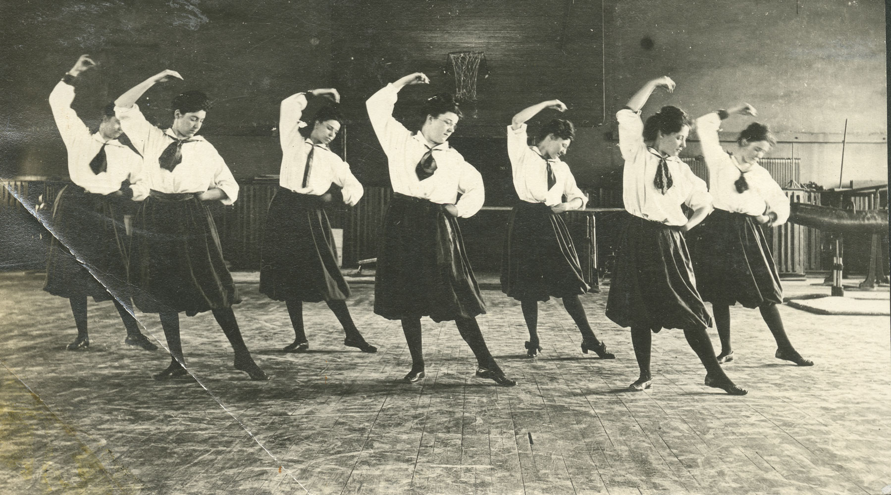 A black and white image of women in skirts stretching