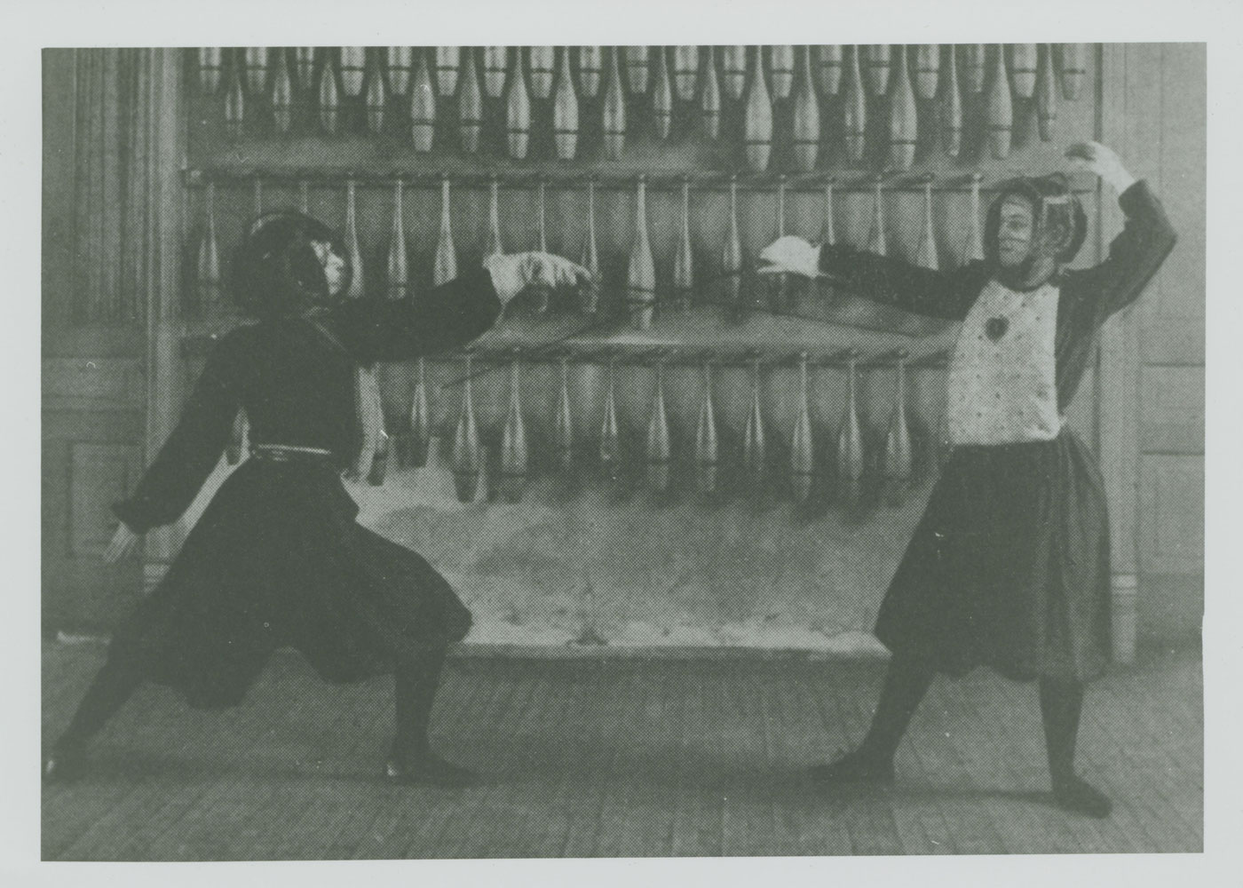 A black and white image of two women fencing