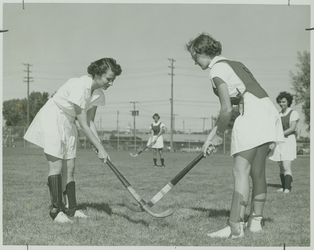 A black and white photo of two women holding hockey sticks