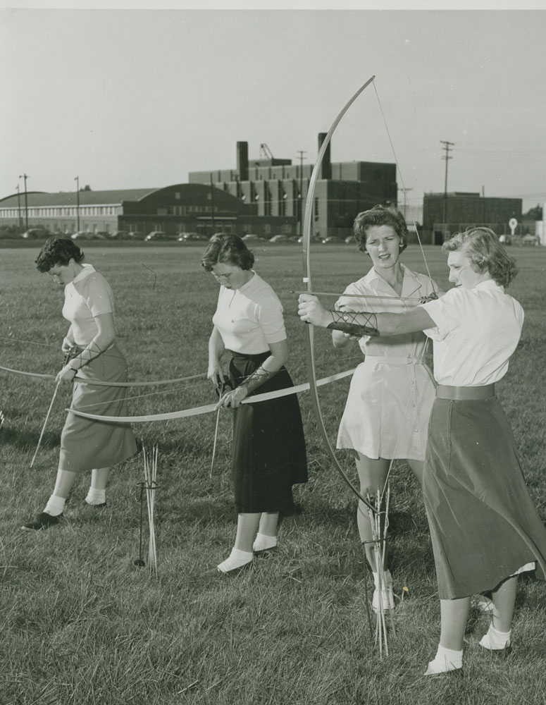 A black and white photo of women practicing archery