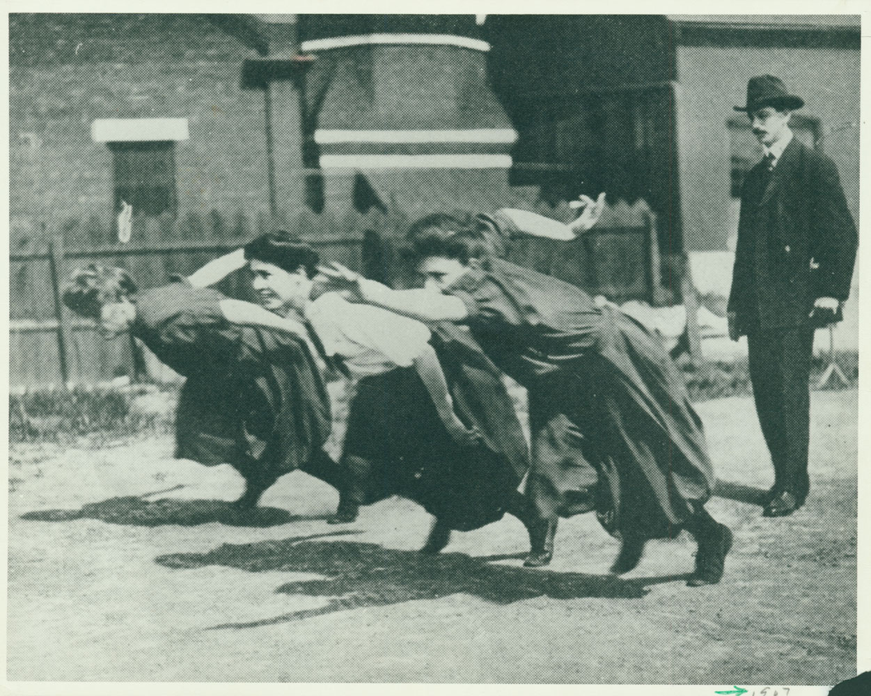 A black and white image of three women racing in dresses
