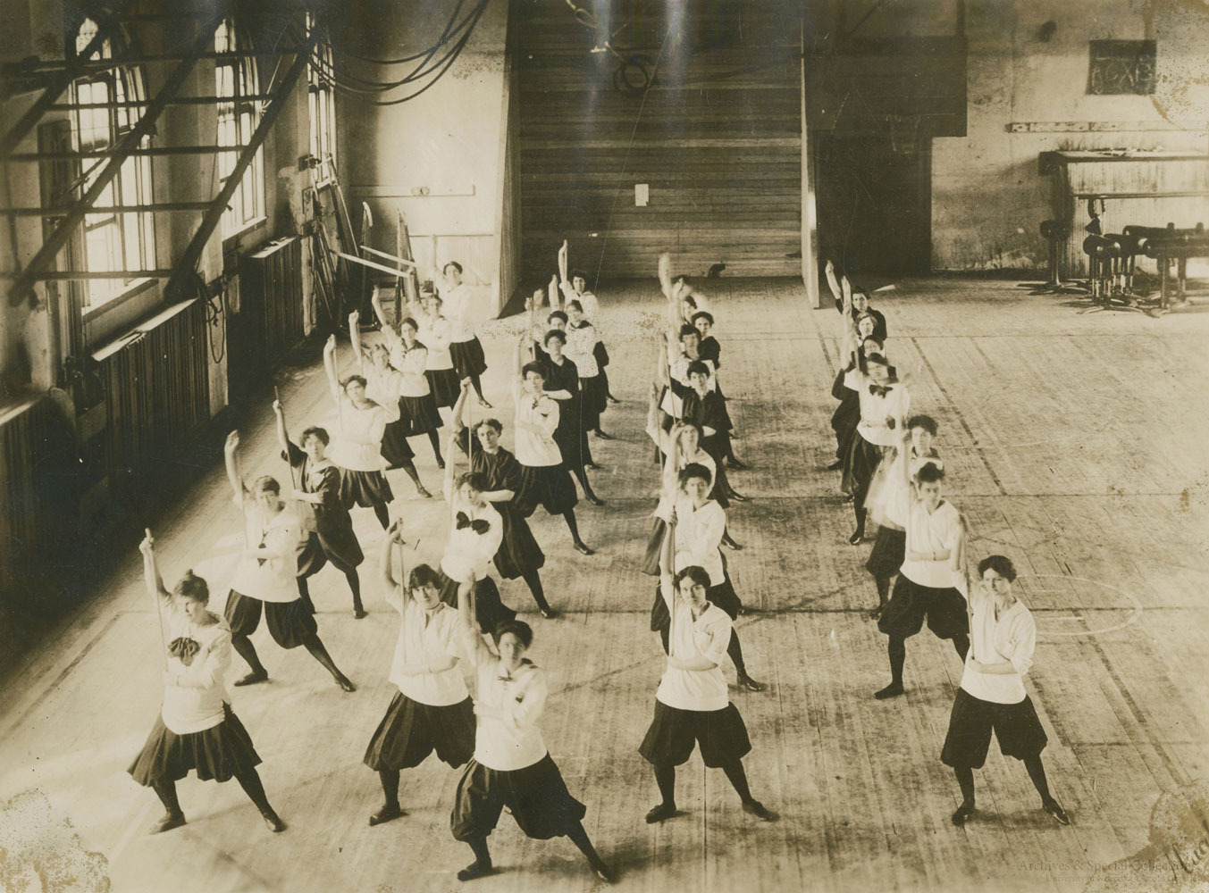 A black and white image of women stretching in a gymnasium