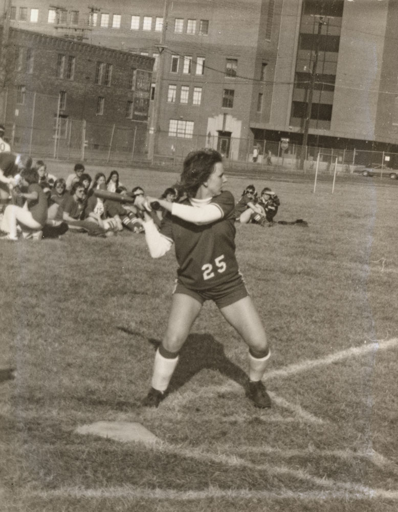 A black and white image of a softball player in batting position