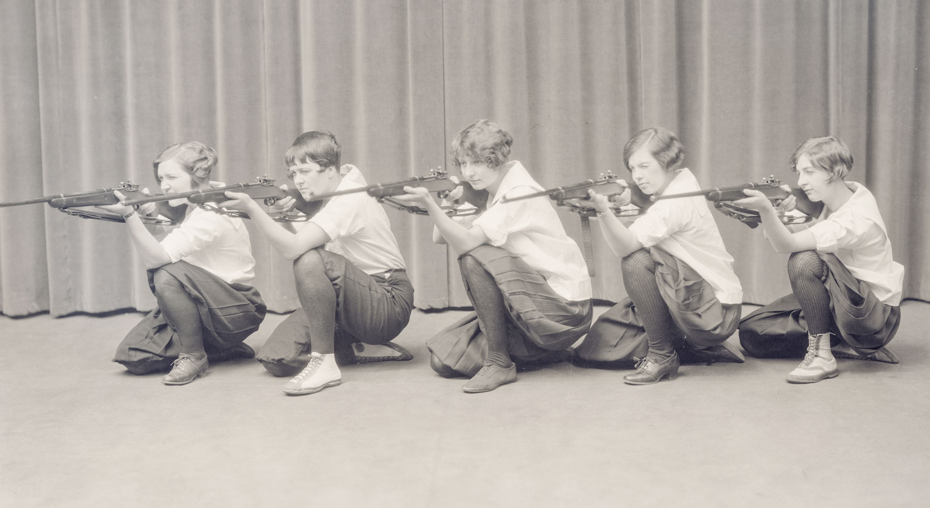 A black and white image of five women aiming rifles